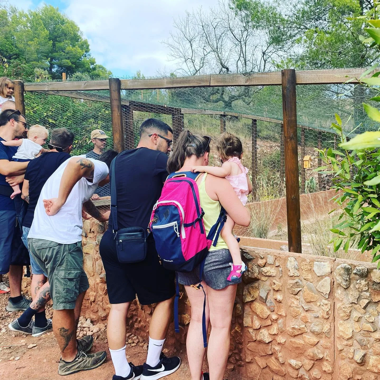 Famílies amb infants observen un recinte de fauna durant una visita a l’aire lliure.